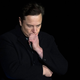 A photo of Elon Musk with his hand on his chin.